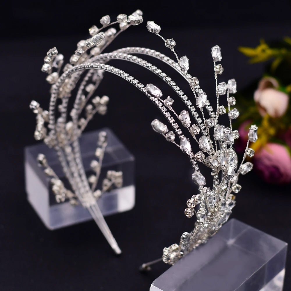 Side-angle view of a silver bridal flower headband with marquise-cut rhinestones and intricate wire branch sprays on a clear display stand.