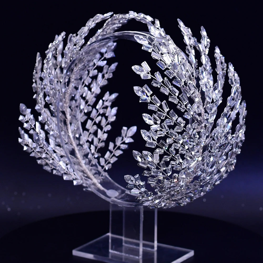 Direct perspective view of a premium silver-plated crystal tiara headpiece featuring sweeping statement leaf branches on an acrylic display.
