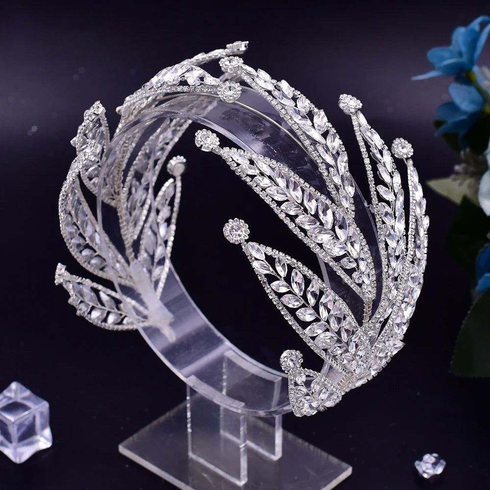 Side-angle view of a silver rhinestone bridal headband tiara with multi-tiered marquise crystal leaf layers on a clear display stand.