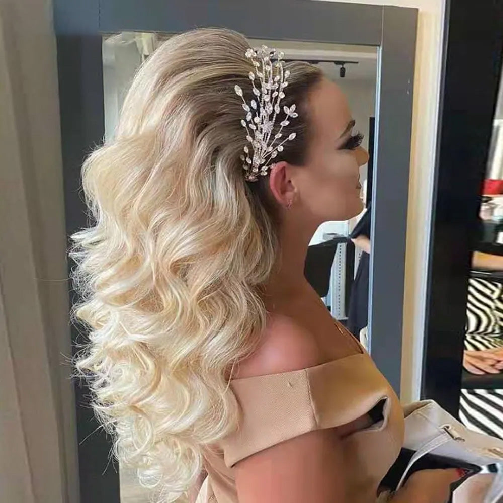 Side profile portrait of a blonde model with a voluminous half-up hairstyle showcasing a sparkling rhinestone bridal headpiece side spray clip.