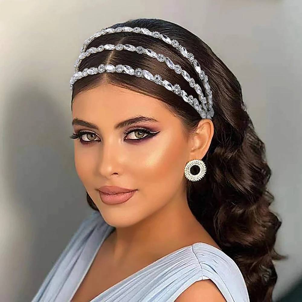 A model wearing a multi-row rhinestone crystal bridal headband with wavy hair and statement earrings.