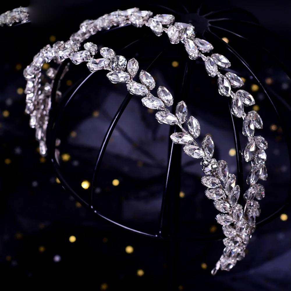 Close-up of a multi-layered crystal bridal headband hair accessory showing marquise-cut rhinestones set on a black structural frame.