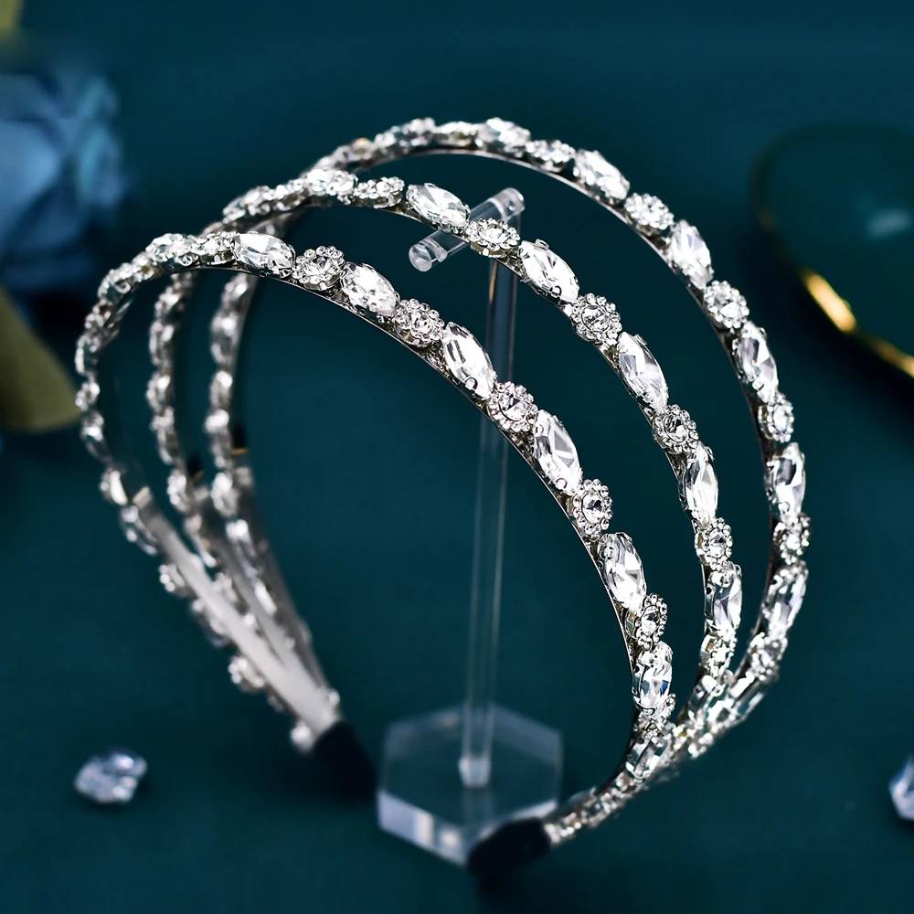 A triple-layer silver rhinestone wedding tiara elegantly positioned on a clear display holder.