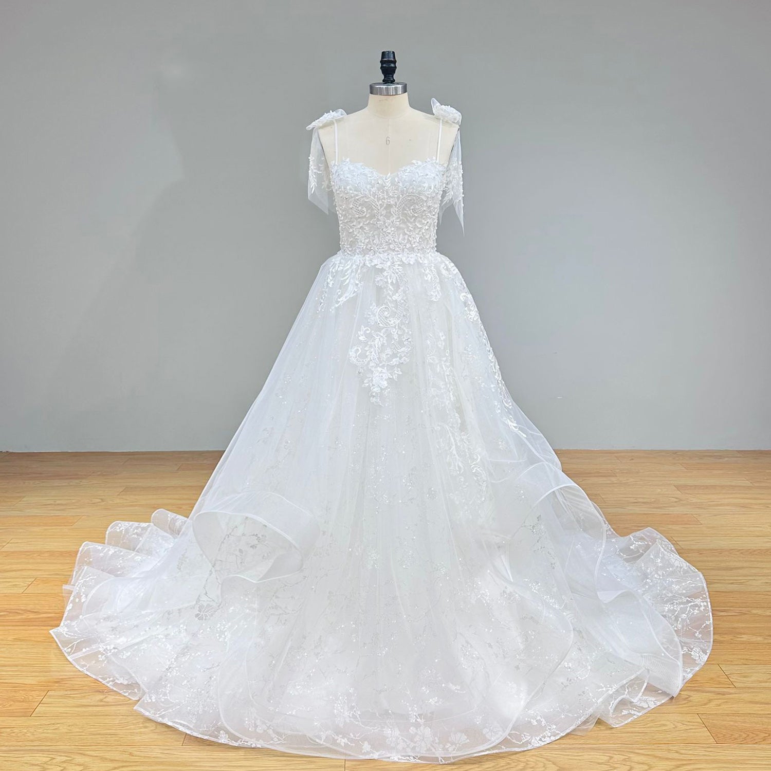 Classic full front studio shot of a sleeveless sweetheart A-line wedding dress on a mannequin, capturing the form-fitting bodice and beautifully draped tulle skirt.