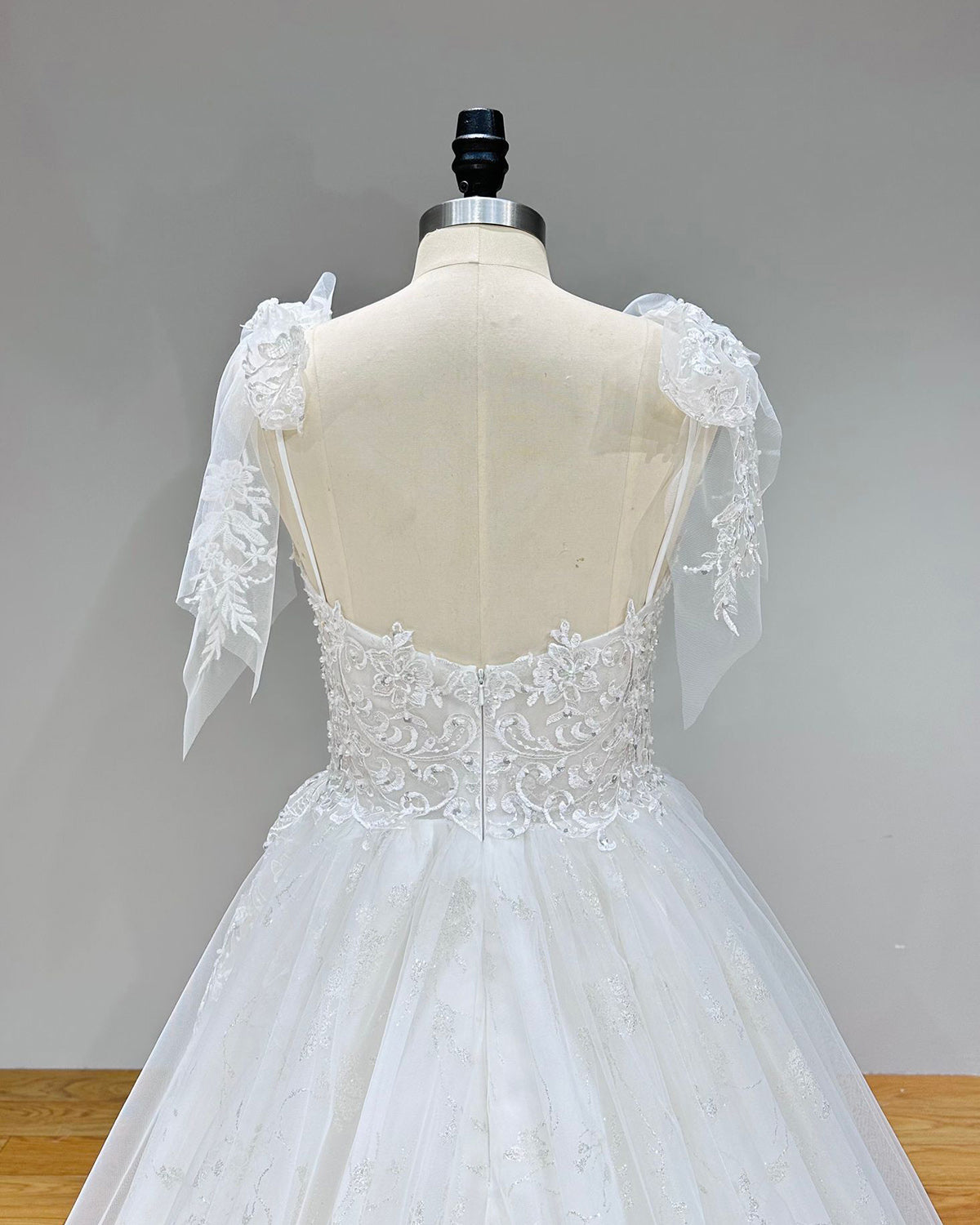 Close-up back bodice view of a robe marriage sweetheart wedding dress on a mannequin, detailing the elegant lace-up back corset over sheer embroidered lace.