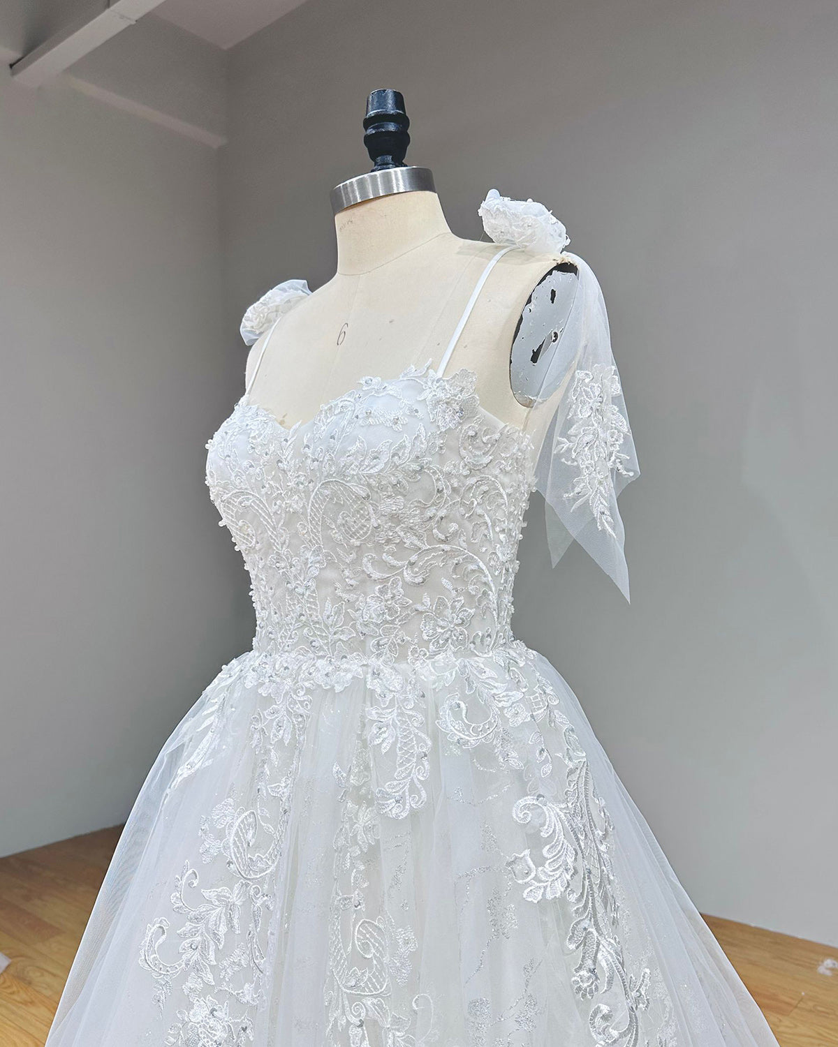 Close-up back bodice view of a robe marriage sweetheart wedding dress on a mannequin, detailing the elegant lace-up back corset over sheer embroidered lace.