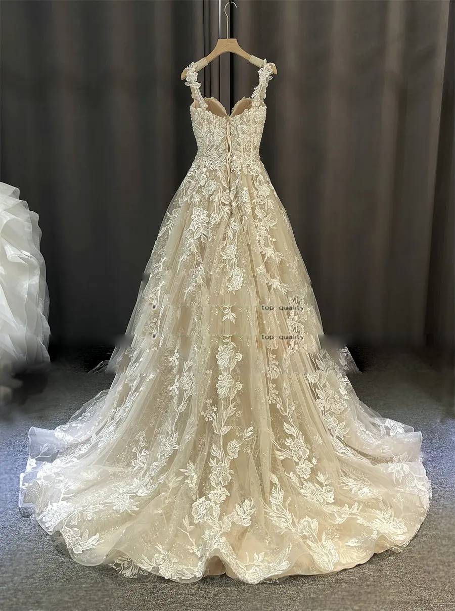 Back view of the romantic A-line lace wedding dress on a hanger, showcasing the lace-up corset and flowing train.