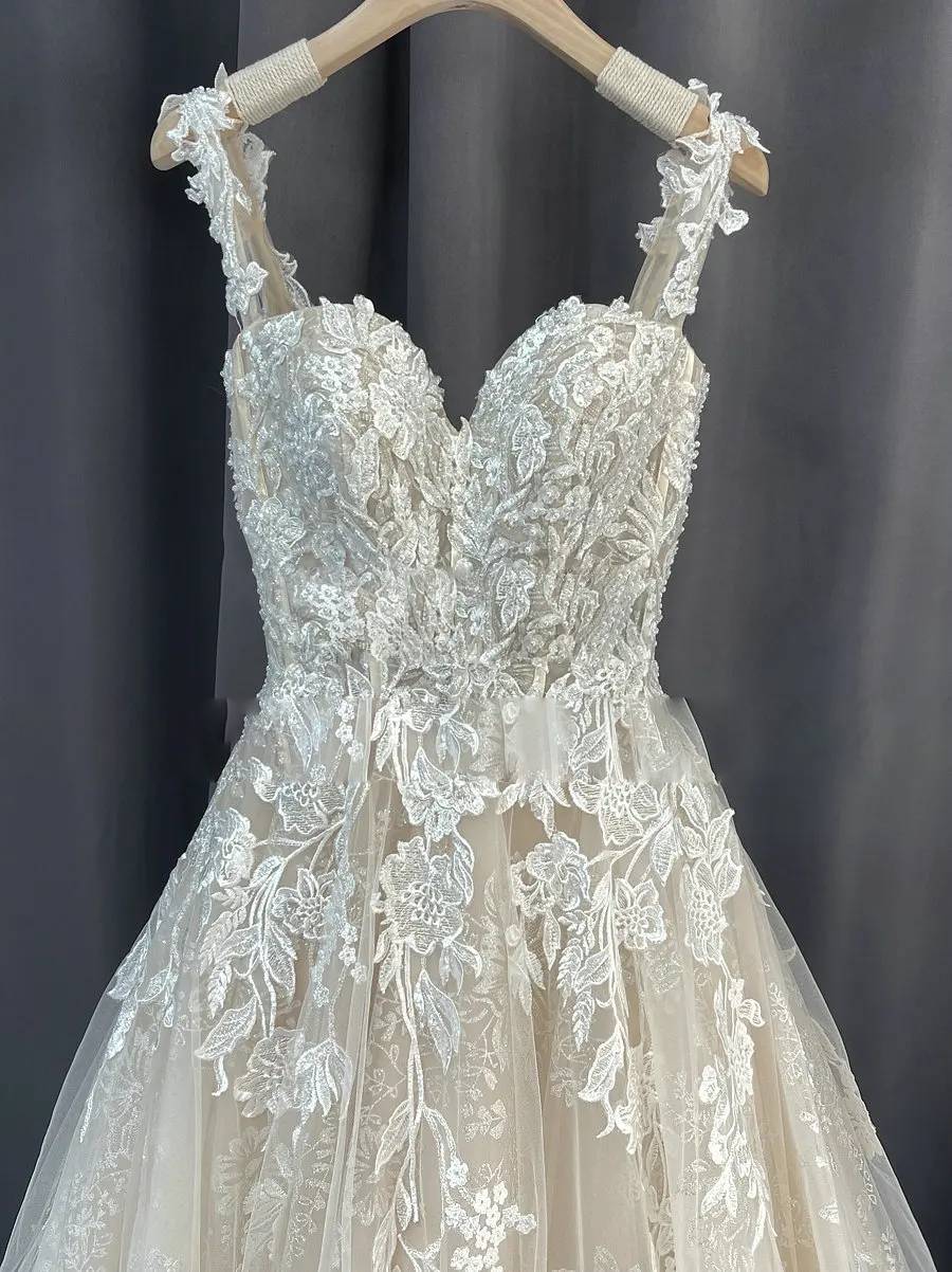 Close-up of the front bodice of the romantic lace bridal dress, detailing the sweetheart neckline and delicate straps.