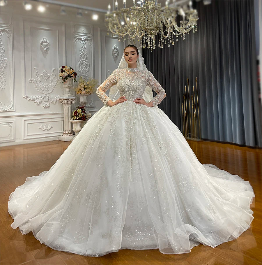 Front perspective of a stunning bride in a romantic high neck lace wedding gown, showing off the intricate floral detailing and shimmering crystal embellishments on the illusion bodice.