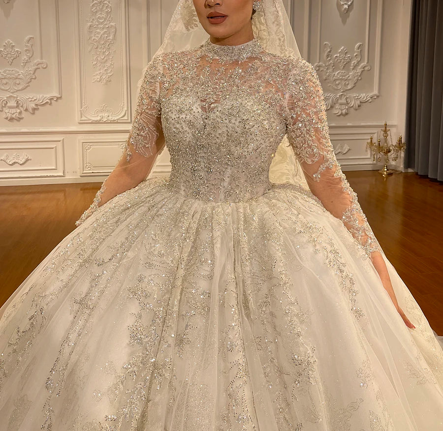 Close-up of the illusion bodice on a romantic high neck lace wedding gown, highlighting the exquisite sheer high collar, heavily beaded long sleeves, and delicate floral appliqués.