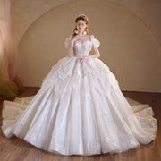 Model wearing a romantic organza ball gown wedding dress featuring a crystal-beaded illusion O-neckline, shimmering glitter tulle skirt, and vintage-style ruffled sleeves.