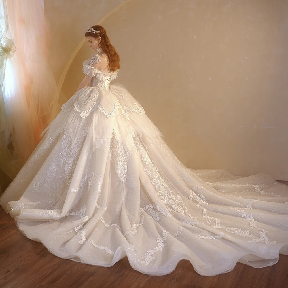 Back view of a luxury full-sleeve bridal gown showcasing a grand cathedral train with intricate scalloped lace appliques and an elegant lace-up corset closure.
