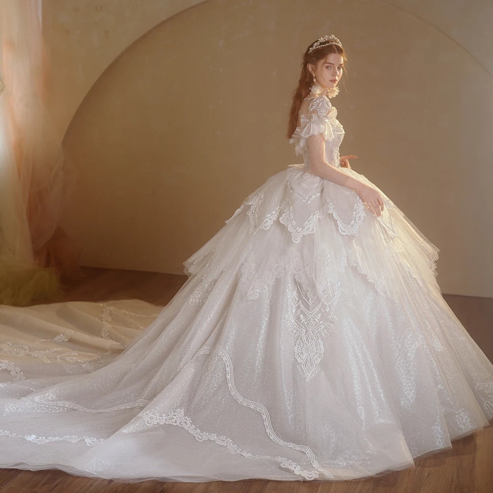 Side profile view of a dramatic fairytale wedding dress featuring layered organza peplum tiers, a sparkling glitter skirt, and a sweeping long train.