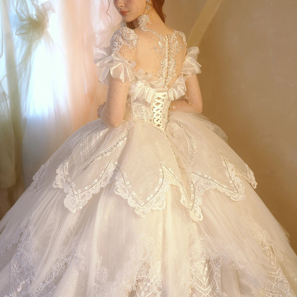 Detailed close-up of a wedding dress back, featuring a sheer illusion mesh panel with crystal beadwork, a row of bridal buttons, and a white lace-up corset closure.