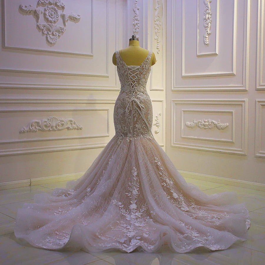Full rear view of an elegant mermaid wedding dress on a mannequin, highlighting the corset back and a sweeping chapel-length floral lace train.