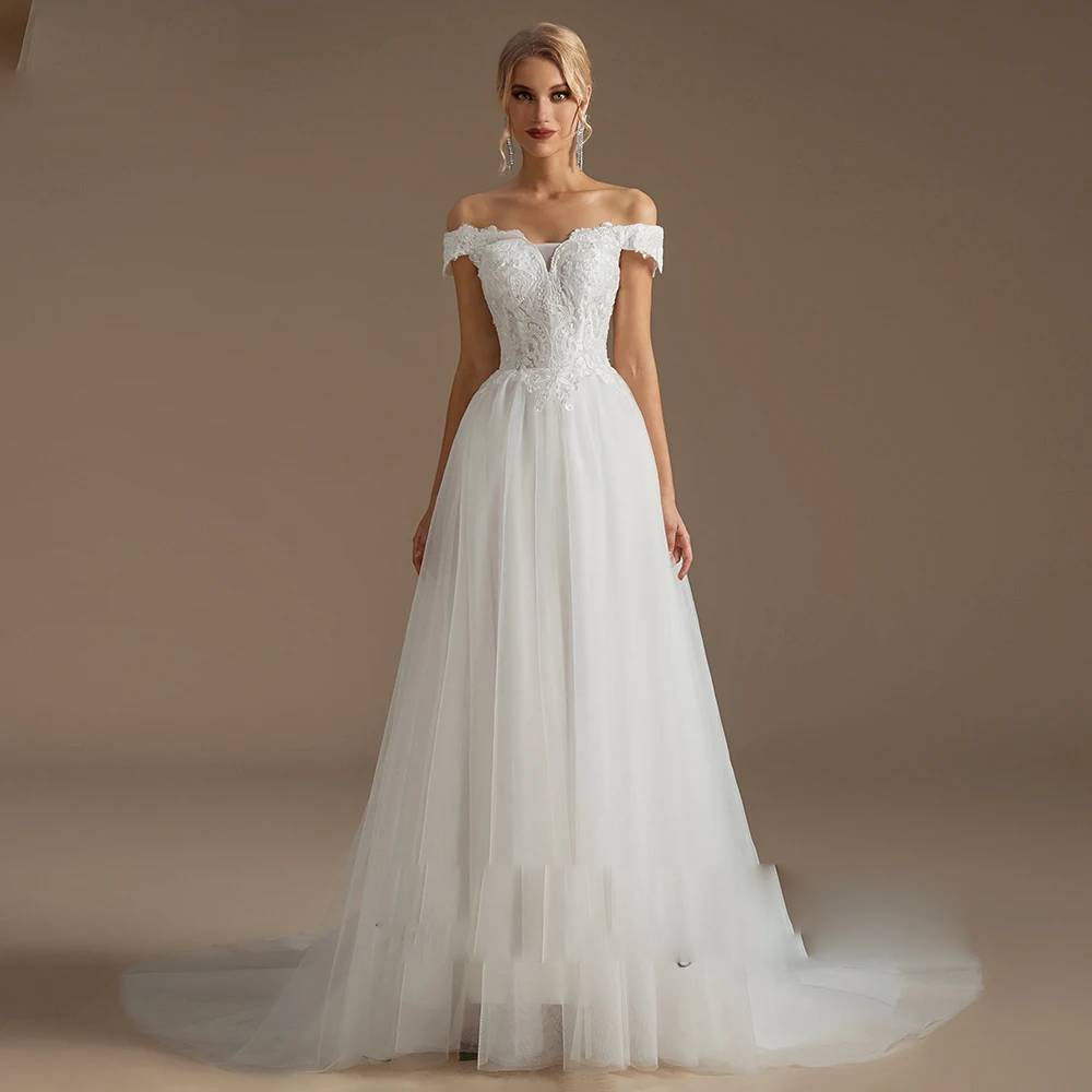 Bride wearing a romantic long sleeve ball gown wedding dress with 3D floral appliques and a sheer illusion neckline at an outdoor beach ceremony under a floral arch.