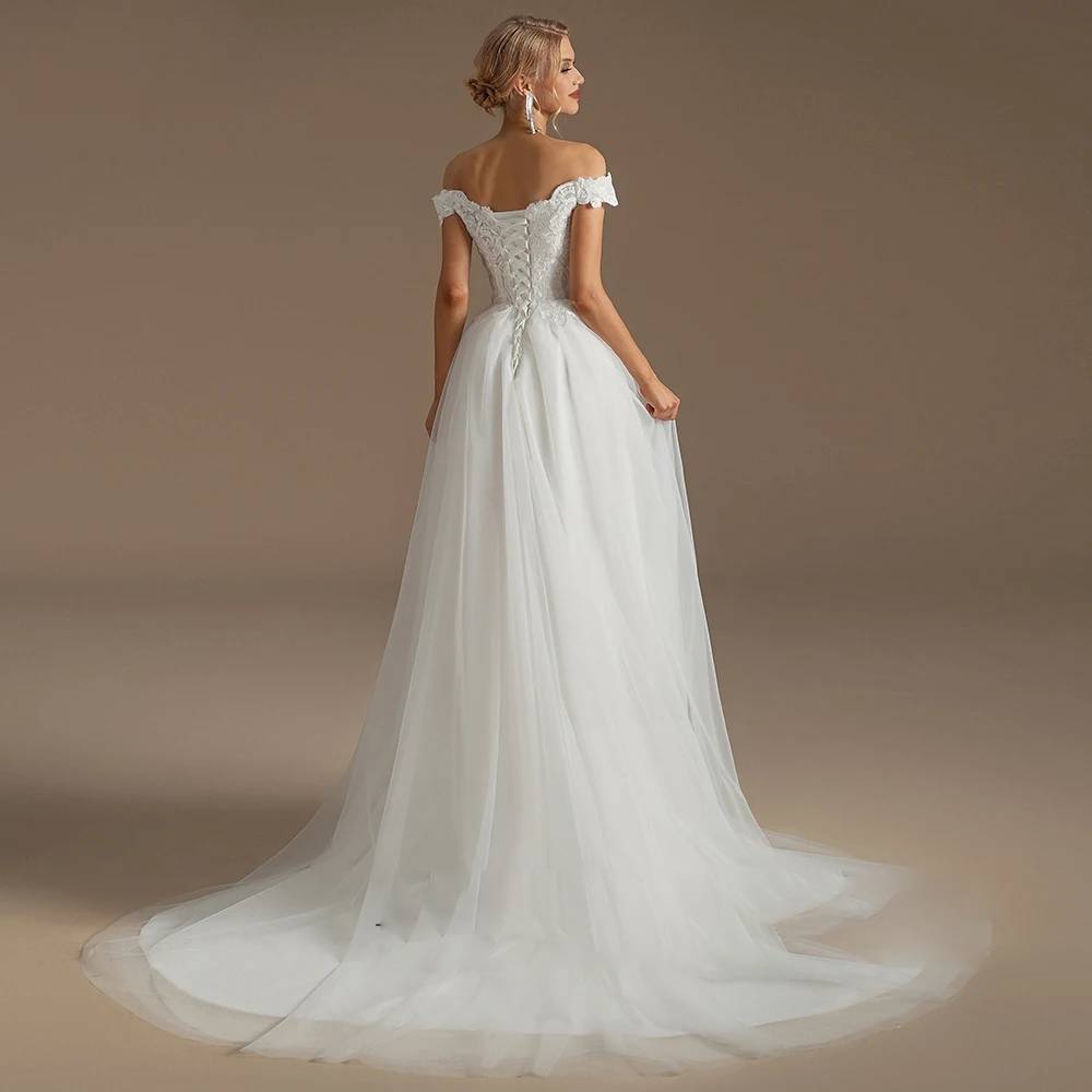 Full back view of a long sleeve bridal ball gown on a mannequin, showcasing an open keyhole back, white lace-up corset closure, and a grand cathedral train.