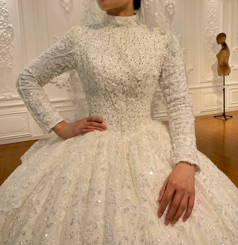 Close-up of the exquisite handmade embroidery and crystal beading on the bodice and long sleeves of a royal Islamic wedding dress, showing the elegant high collar.