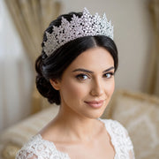 Headshot portrait of a bride with an elegant dark updo hairstyle wearing a high-set Royal Queen bridal tiara crafted with clear marquise crystal blossoms.