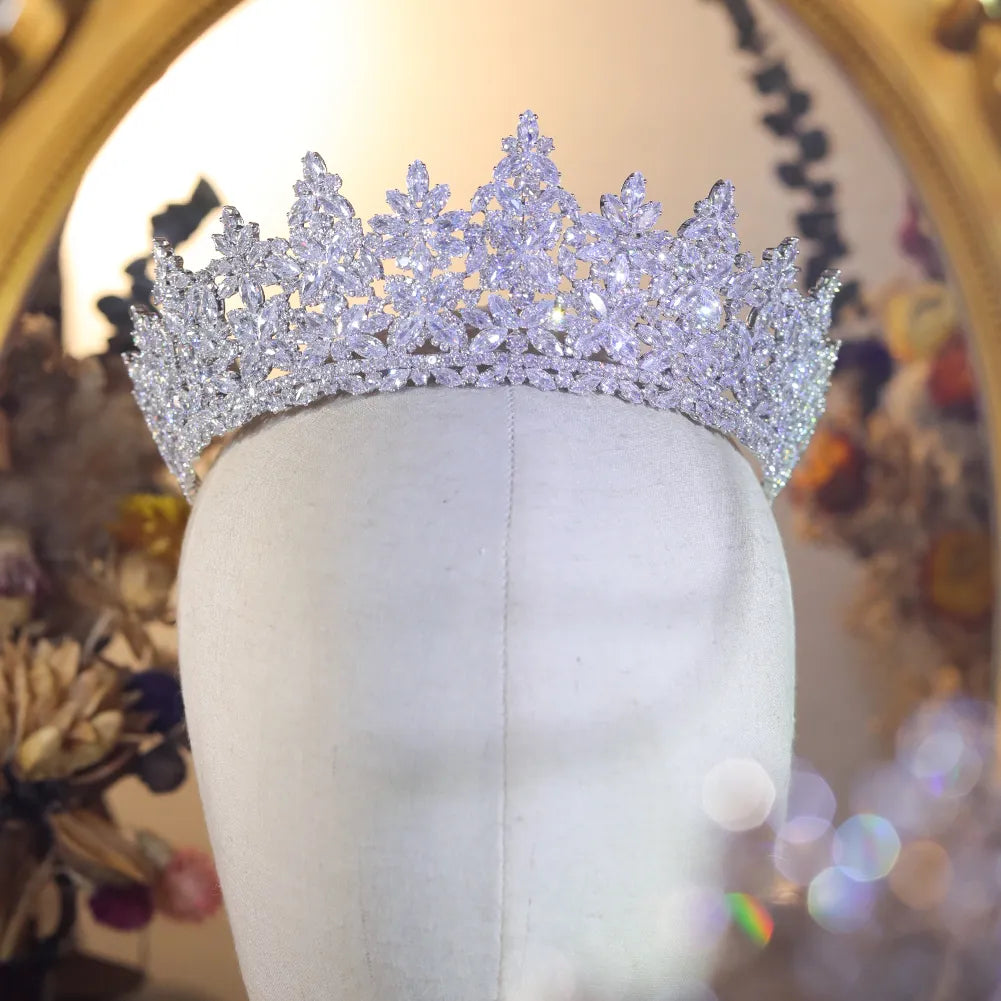 Direct view of a luxurious platinum-plated bridal diadem crown styled elegantly on a white mannequin head piece near a gold vanity mirror.
