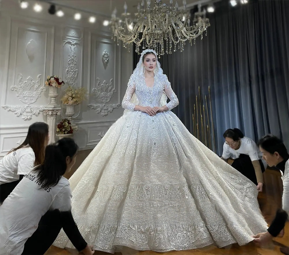 Elegant front view of a shimmering royal princess ball gown featuring long sleeves and decorative tiered lace borders on a grand, multi-layered cathedral skirt.