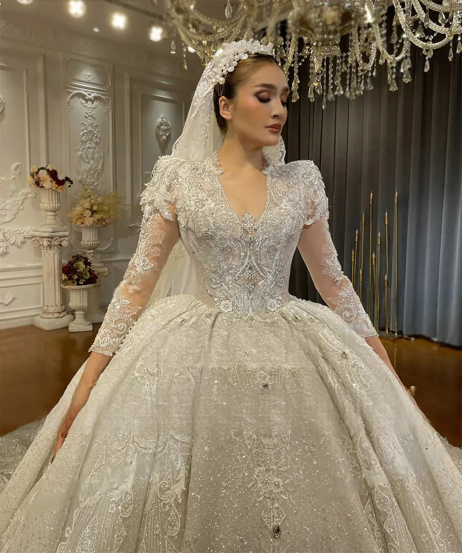 Detailed close-up of 3D lace appliques and a deep V-neckline on a luxury long sleeve wedding gown, featuring a matching floral-embellished bridal headpiece and veil.