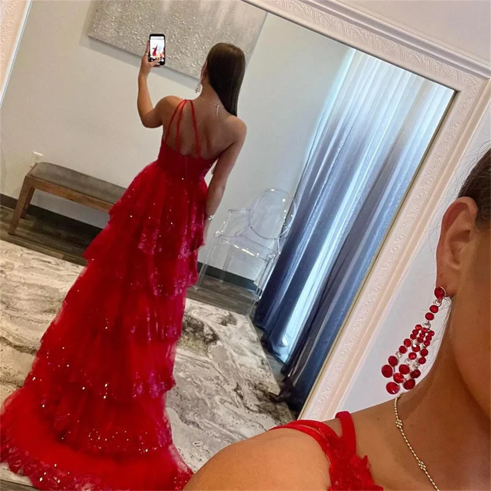 Rear view mirror selfie of a ruby red Sansa glitter evening dress highlighting the elegant multilayer tiered skirt and delicate thin lace-up back straps.
