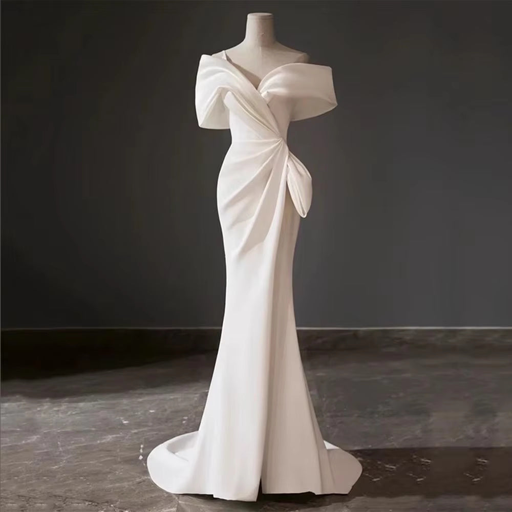 Contemporary off-the-shoulder silk wedding dress with a high leg slit, styled with a modern mesh birdcage face veil for an editorial bridal look.