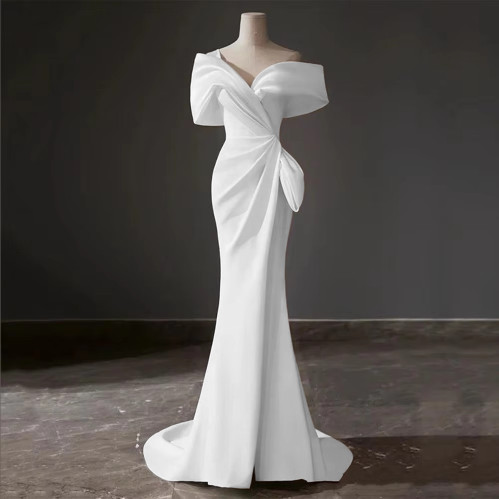 Close-up of a structured satin wedding gown bodice showcasing a crisp overlapping off-shoulder neckline and a deep sweetheart plunge with a sheer insert.