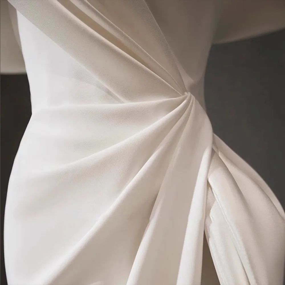 Stately pure white satin mermaid wedding dress with an asymmetric draped off-the-shoulder neckline and a clean, seamless floor-length skirt.