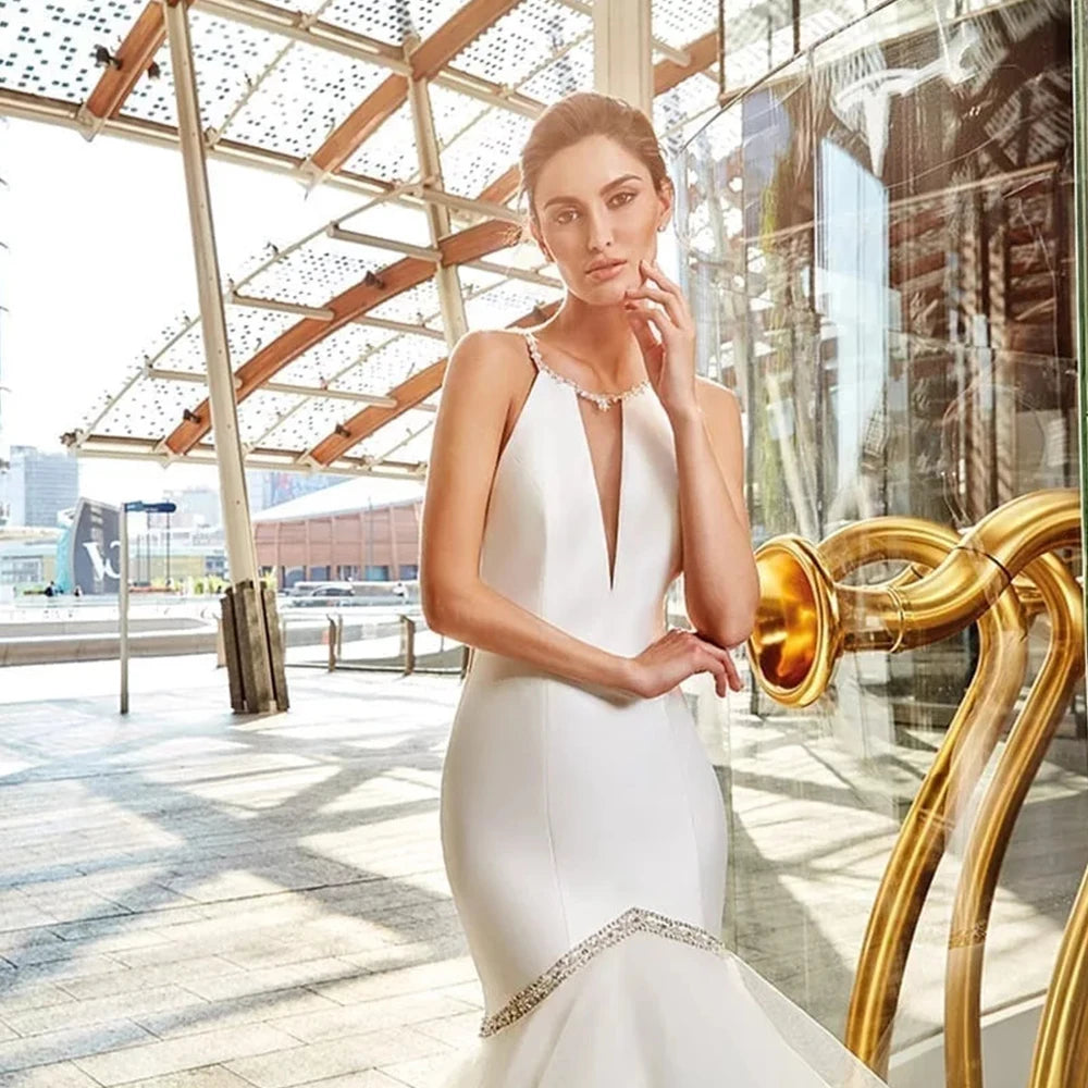 Close-up front view of a minimalist halter neck wedding dress bodice, highlighting a sheer plunge slit, delicate silver rhinestone accents, and smooth premium satin fabric construction.