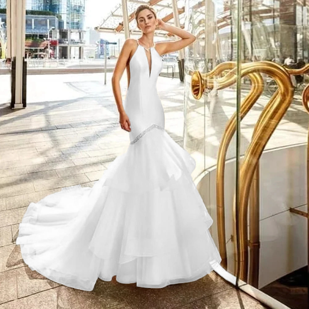 Crisp pure white vestibido de noiva sereia with a halter keyhole bodice and an architectural tiered tulle flared maxi skirt line, ideal for a modern outdoor wedding.