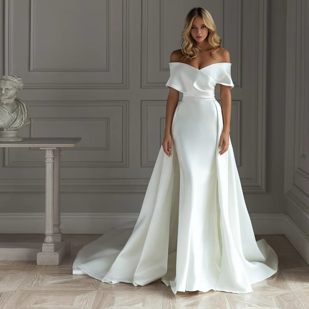 Minimalist satin mermaid wedding dress featuring a structured off-the-shoulder portrait collar, a plunging V-neckline, and a grand detachable satin overskirt train.