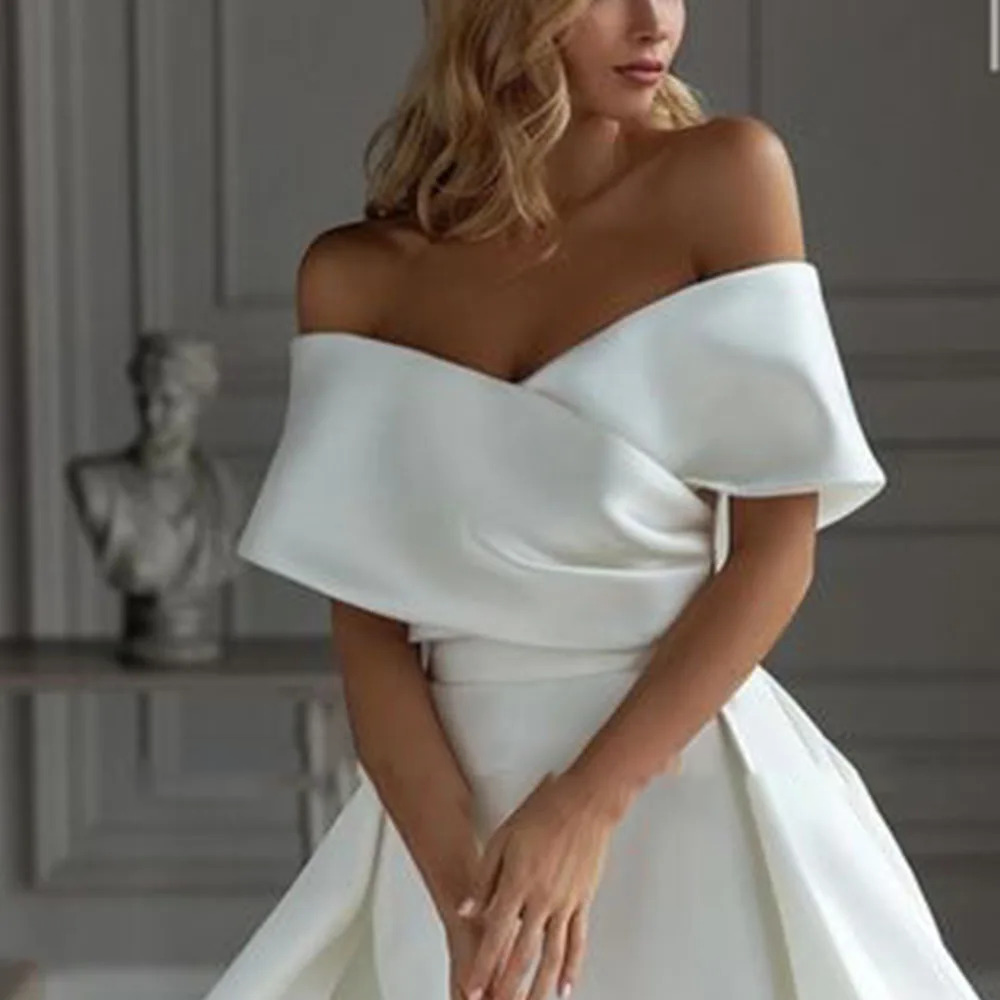 Close-up of a modern satin bridal bodice highlighting clean draped off-the-shoulder cuff sleeves and a beautifully tailored overlapping sweetheart neckline.