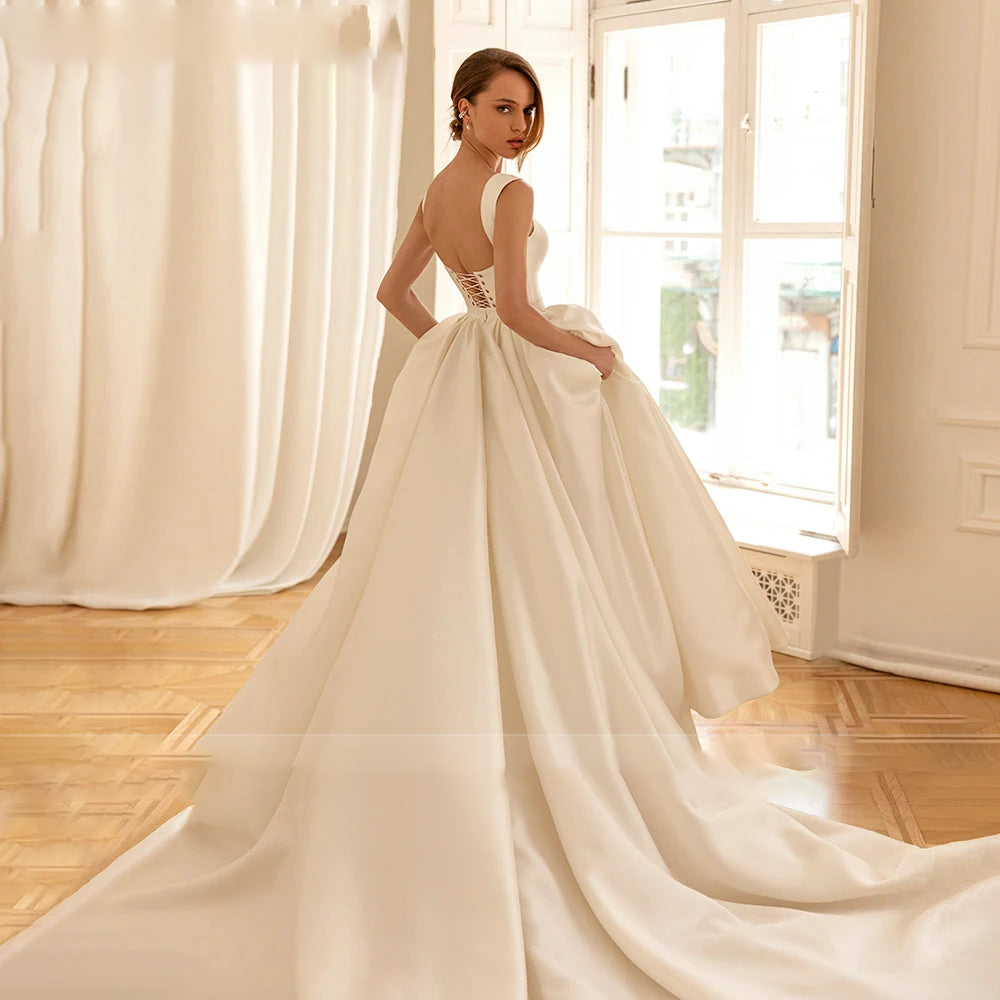 A rear view of a bride in an elegant ivory A-line wedding gown, emphasizing the corset-style back and voluminous train.