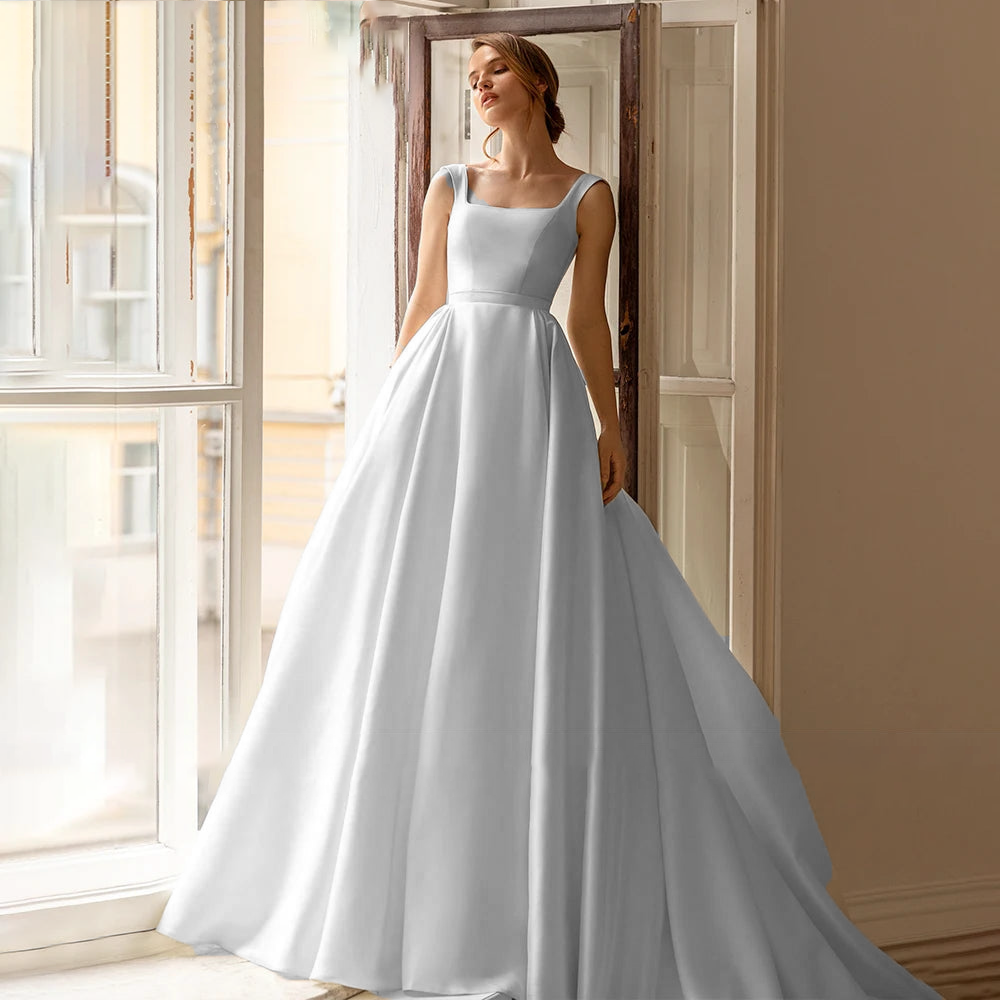 A bride posing in a simple, sleeveless ivory A-line bridal gown, perfect for a timeless and sophisticated wedding look.