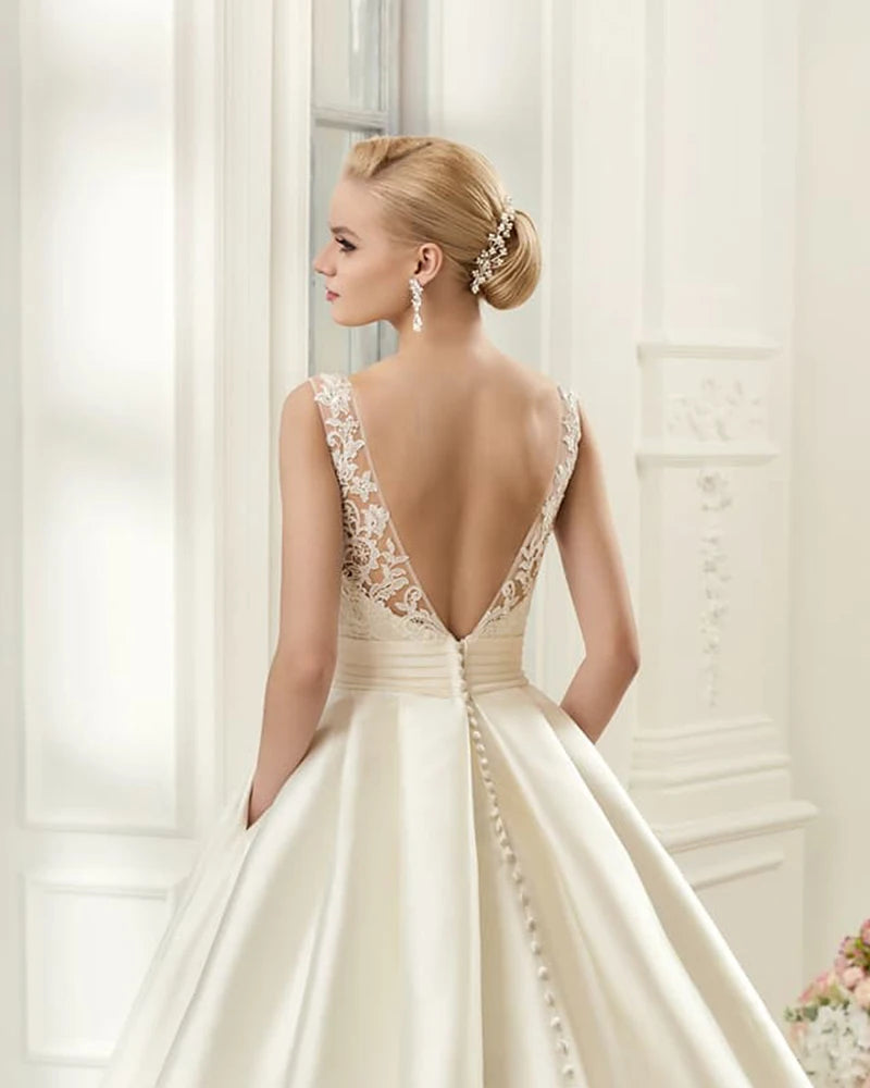 Back profile of an elegant satin A-line wedding dress featuring an open-back design and a row of delicate buttons.