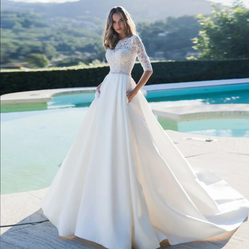 A beautiful satin A-line wedding dress highlighting an elegant scoop neck, lace appliques, and a sophisticated beaded waist sash.