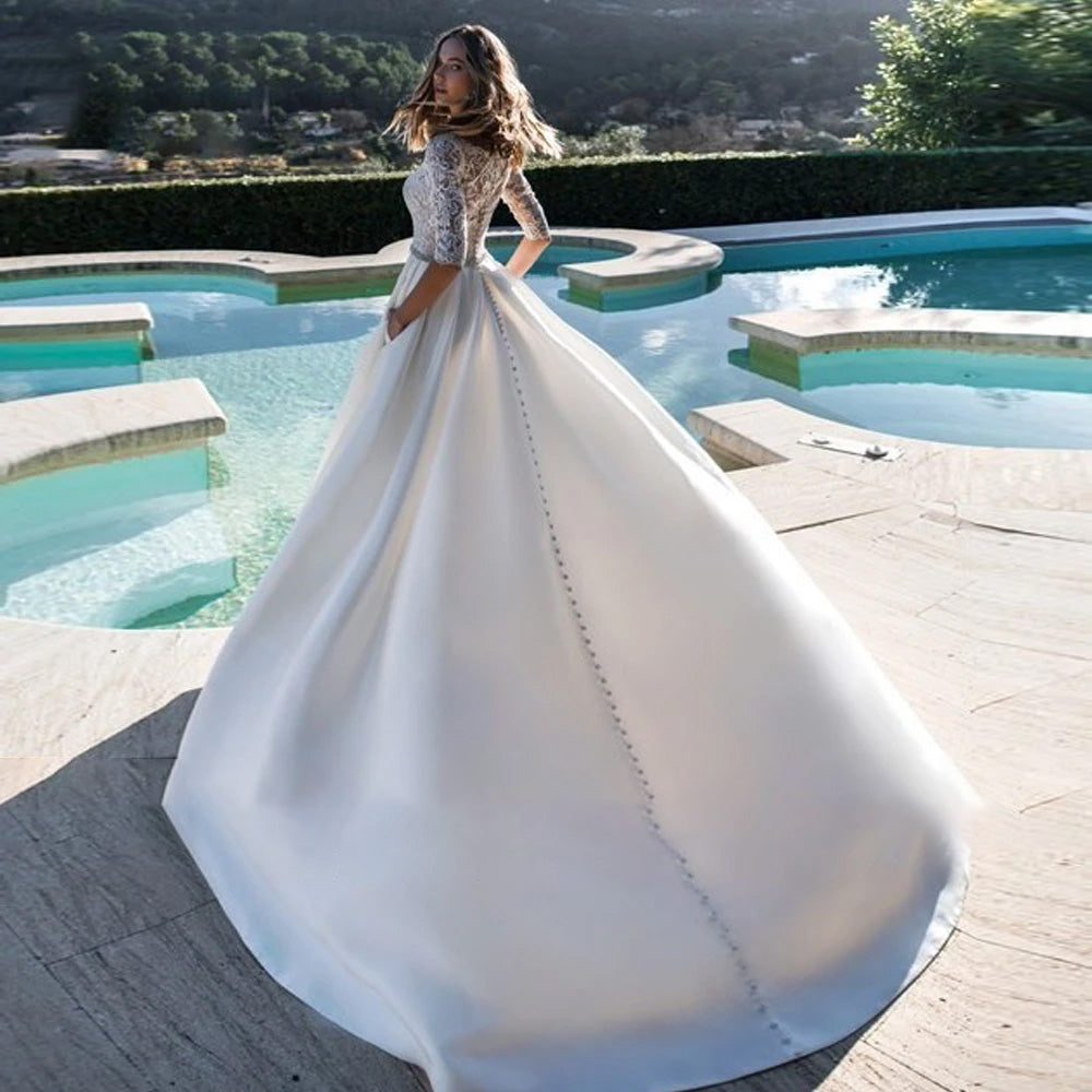 The back view of a luxury satin A-line wedding dress, showcasing elegant button-back detailing, a beaded waist sash, and a sweeping court train.