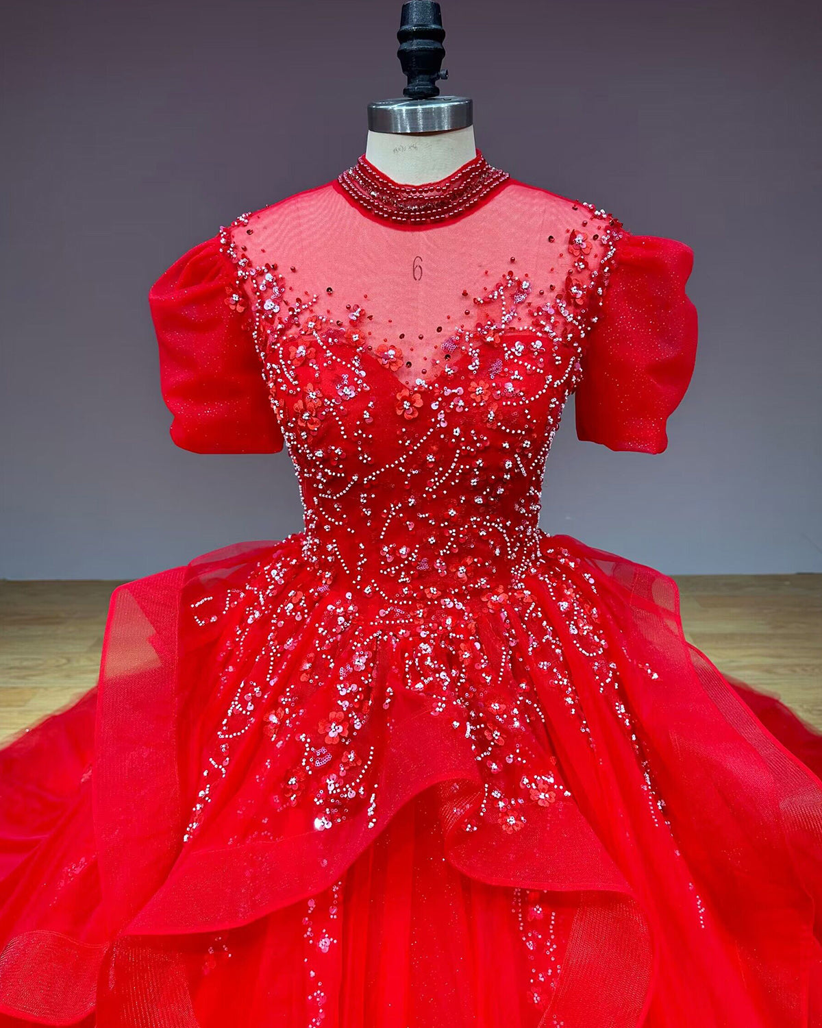 Straight-on front close-up of a red high-neck wedding dress bodice, illustrating the fine sequin patterns, 3D flowers, and sweetheart inner lining.