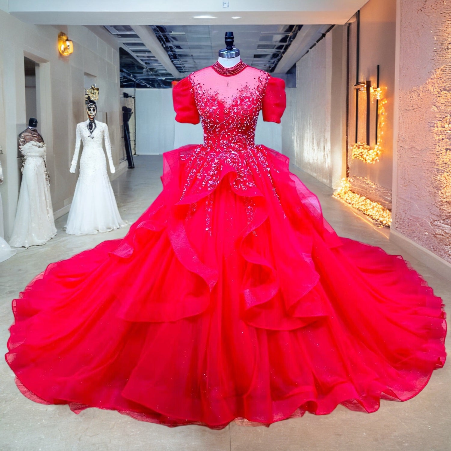 Full-length front view of a red sequin ball gown wedding dress displayed on a mannequin in a bright bridal showroom corridor.