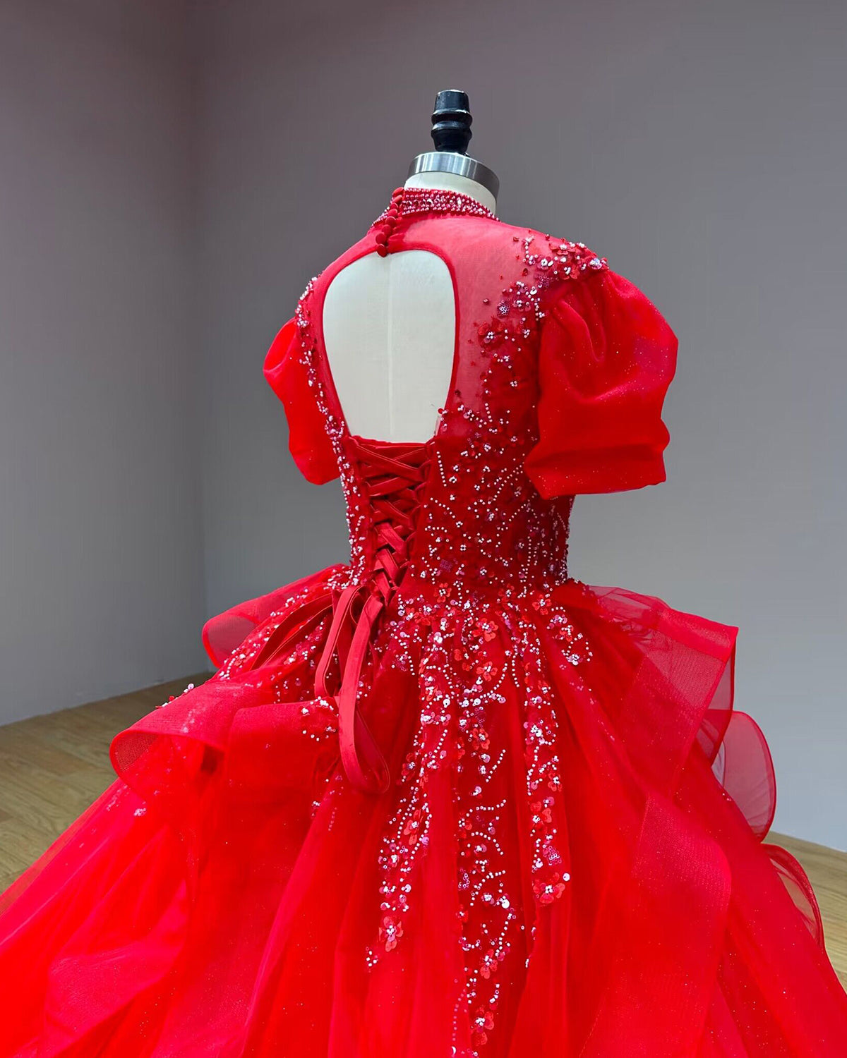 Angled rear close-up of a red high-neck sequin wedding dress bodice highlighting the keyhole back cut-out and shimmering beadwork over tulle.