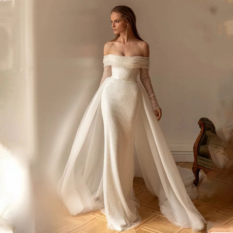 Elegant off-shoulder mermaid wedding dress featuring shimmering sequins, long sheer sleeves, and a detachable train for a versatile bridal look.