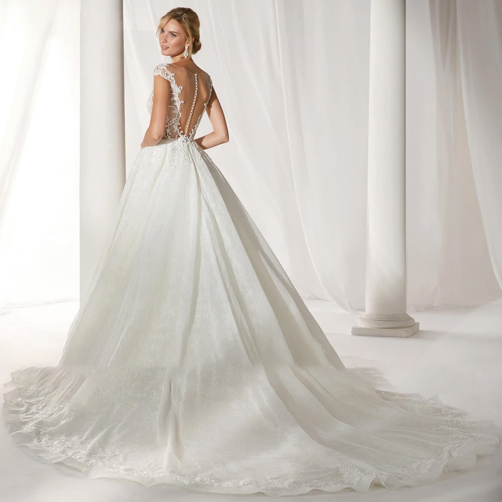 Rear view of an exquisite A-line princess wedding dress showcasing a scalloped backless design with button detailing and a sweeping court train.
