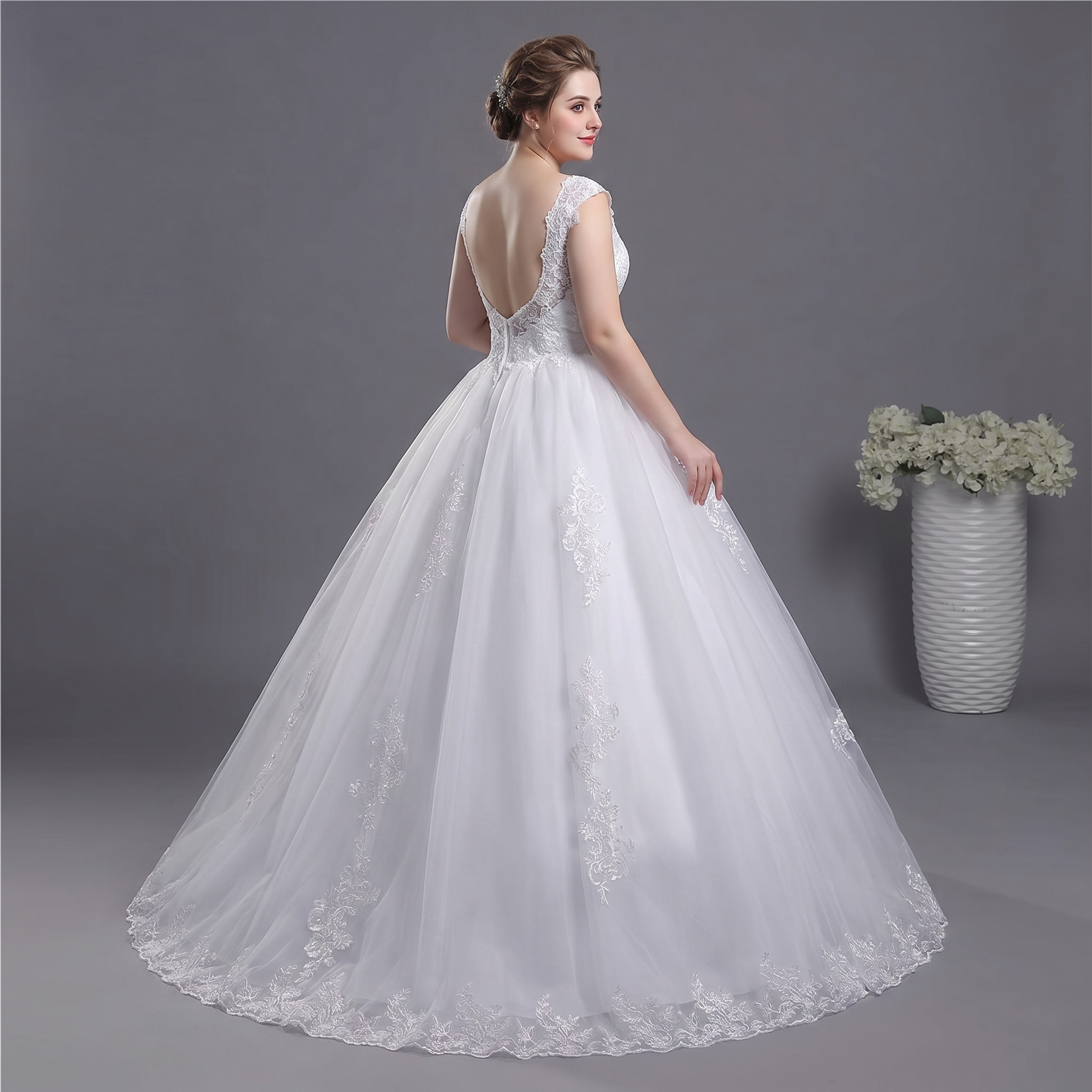 Back view of a bride wearing a sexy backless A-line lace bridal gown with intricate detailing.