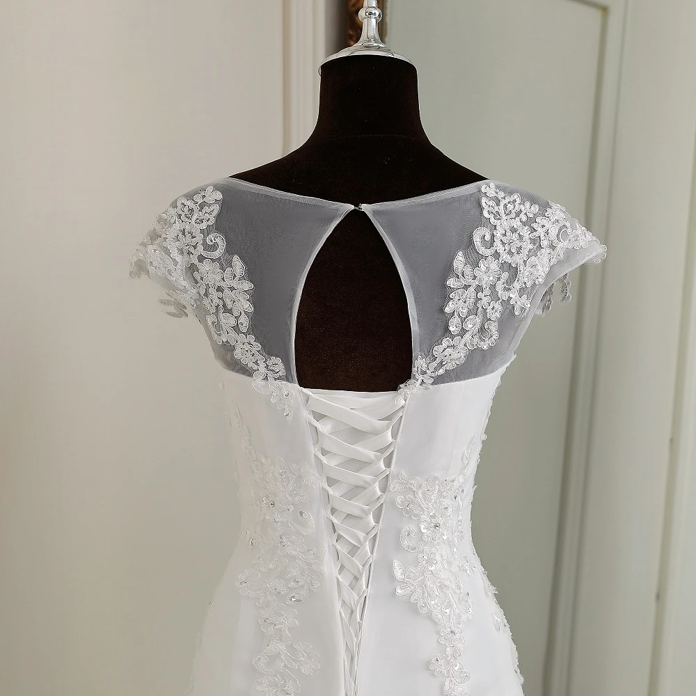 A detailed close-up of the delicate lace cap sleeves and sheer illusion neckline on the bridal gown.