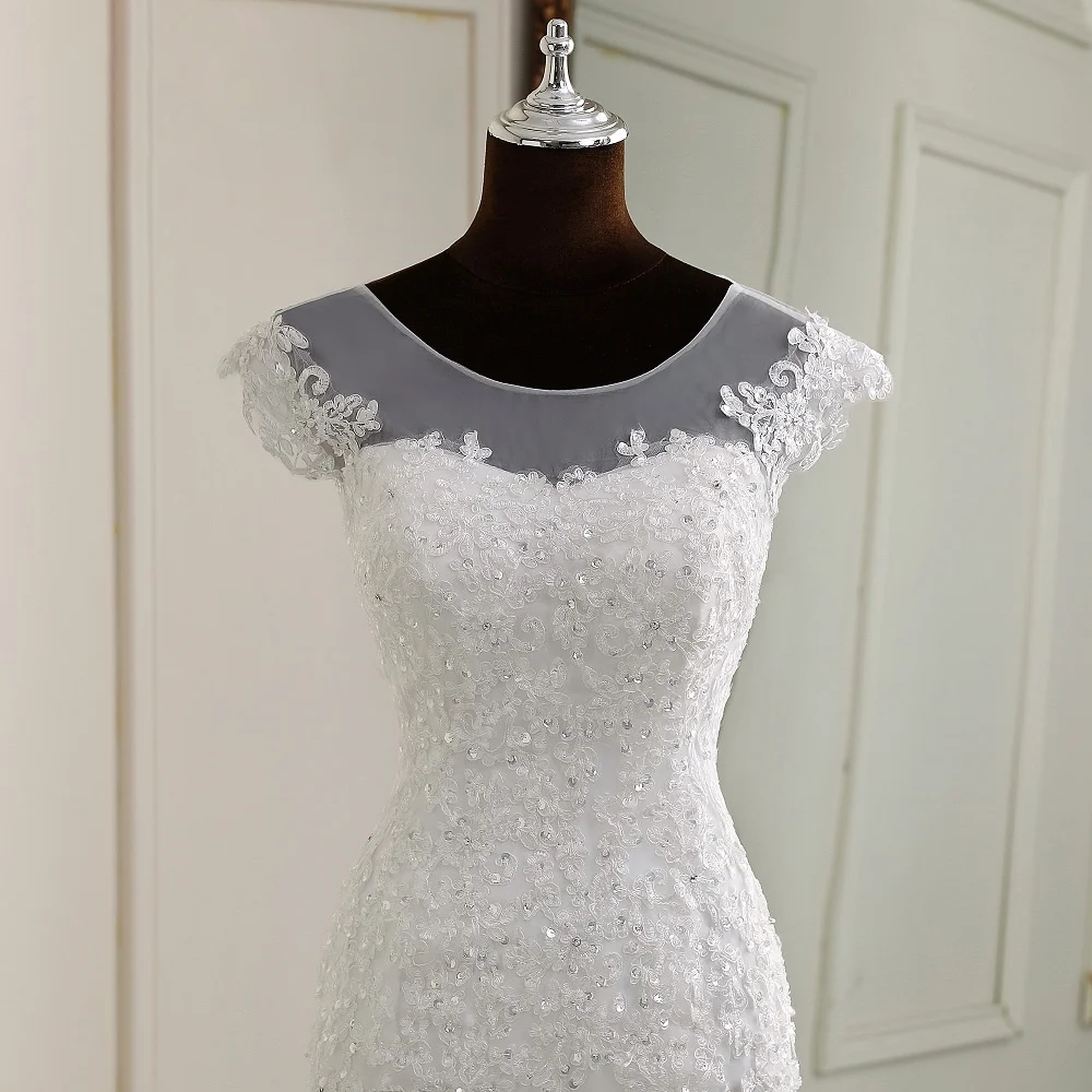 Full-length rear view of a cap-sleeve mermaid bridal gown on a mannequin, showcasing the corset back design and chapel train.