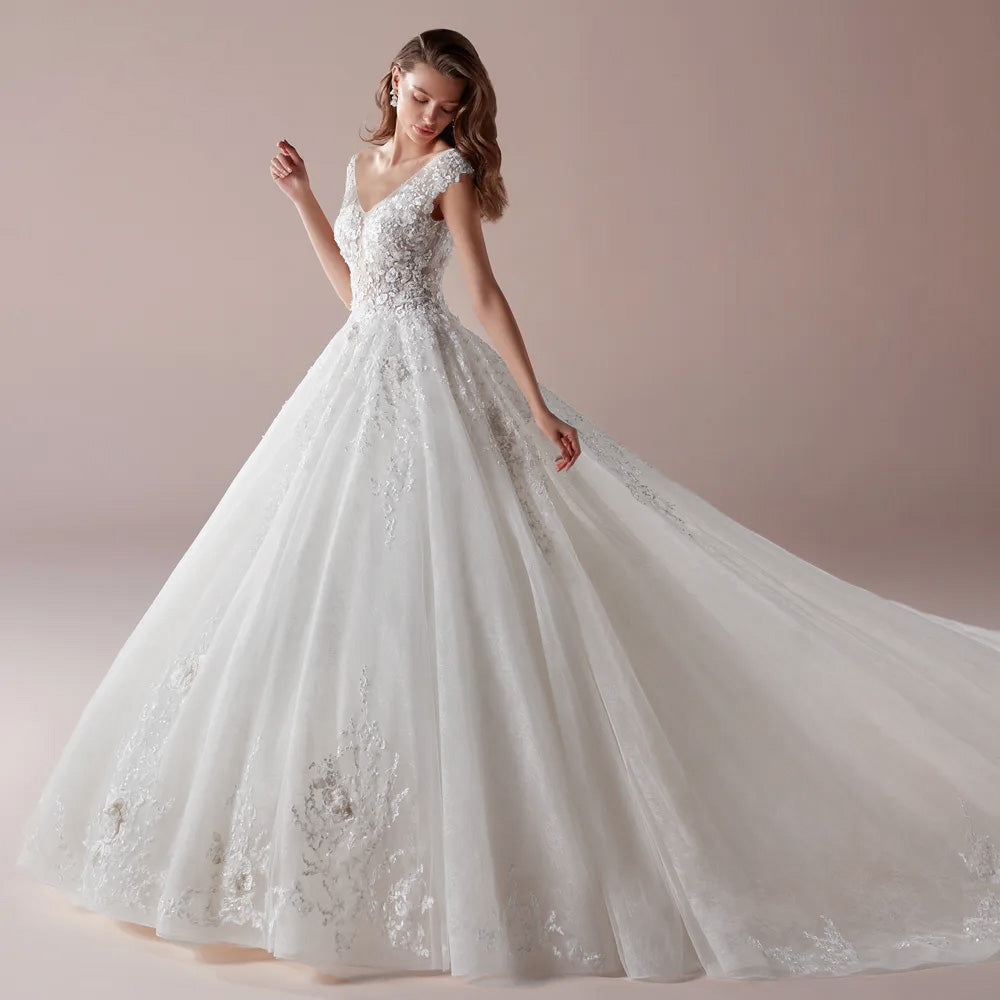 A side profile of a bride wearing an elegant V-neck A-line wedding dress featuring intricate floral lace appliques and a long, flowing chapel train.