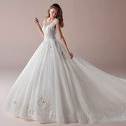A side profile of a bride wearing an elegant V-neck A-line wedding dress featuring intricate floral lace appliques and a long, flowing chapel train.