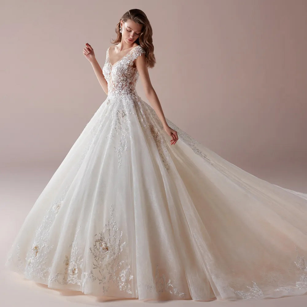 A closer, three-quarter view of a bride modeling a V-neck A-line bridal gown with delicate floral lace embellishments and a voluminous tulle skirt.